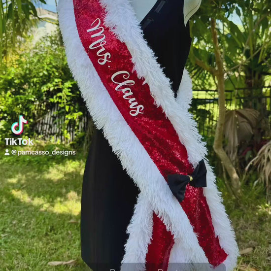 Add a festive touch to your holiday look with this vibrant red sequin “Mrs. Claus” sash! Trimmed in soft, white faux fur for a cozy, wintery feel, this sash catches the light with every step. A chic black satin bow with a gold accent adds a pop of elegance, completing the classic Christmas-inspired design.