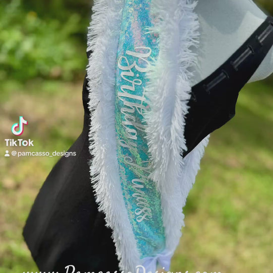 Make any celebration unforgettable with our Ice Blue Iridescent Sequin Sash! This dazzling sash features shimmering ice blue sequins that catch the light beautifully, giving it a magical glow. Trimmed with soft white faux fur for a touch of elegance, it’s adorned with ‘Birthday Princess’—or personalized with a custom message for that extra-special touch. Finished with a classic white satin bow closure, this sash is perfect for birthdays, photoshoots, or any occasion where you want to feel like royalty